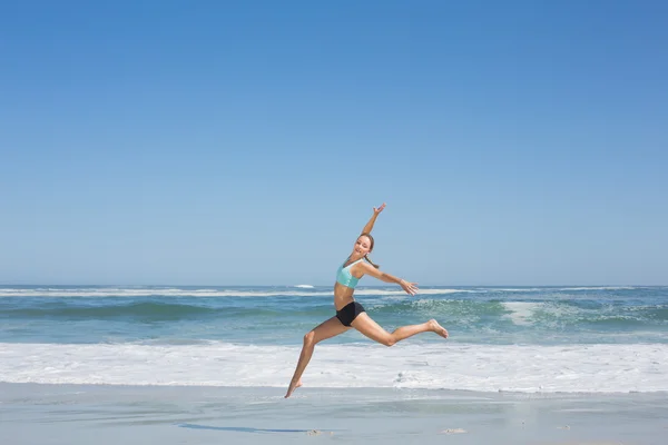 Женщина грациозно прыгает по пляжу — стоковое фото
