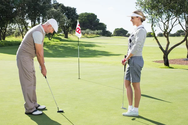 Golfové pár na putting green na osmnáctém díry — Stock fotografie