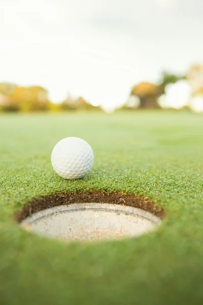 Golf ball at edge of hole — Stock Photo, Image