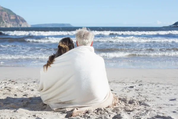 Casal sentado na praia sob cobertor — Fotografia de Stock