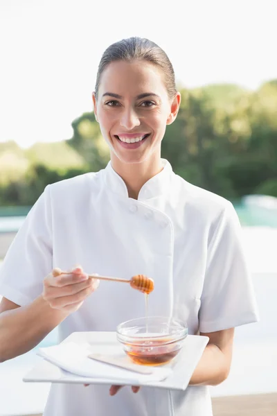 Beauty therapist holding plate with honey — Stock Photo, Image