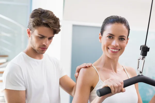 Vrouw met behulp van gewichten machine met traine — Stockfoto