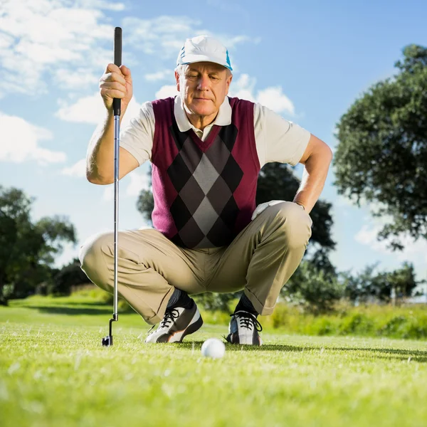 Golfer kniend vor goldenem Ball — Stockfoto