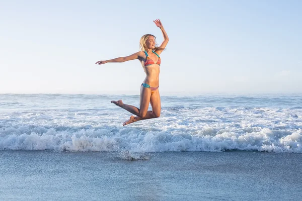 Blonde springen op strand — Stockfoto