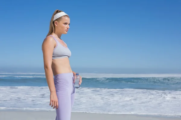 Sportovní blondýna na pláži s láhev s vodou — Stock fotografie