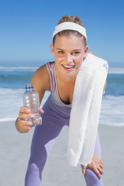 Bionda sportiva sulla spiaggia con asciugamano e bottiglia — Foto Stock