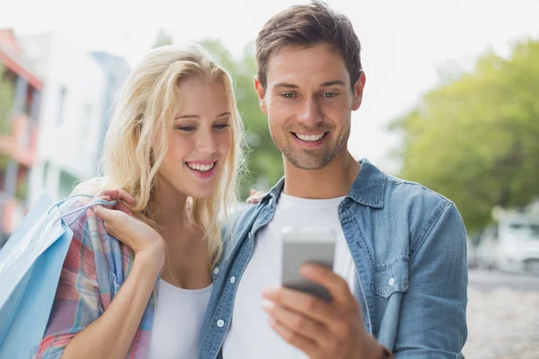 Пара смотрит на смартфон во время шоппинга — стоковое фото