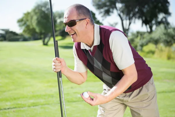 Excited golfer holding ball and club Royalty Free Stock Images