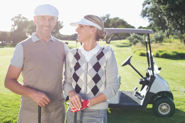 Casal de golfe com buggy de golfe atrás — Fotografia de Stock