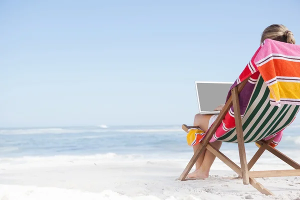 Vrouw in ligstoel met behulp van laptop — Stockfoto