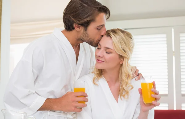 Couple in bathrobes drinking juice — Stock Photo, Image