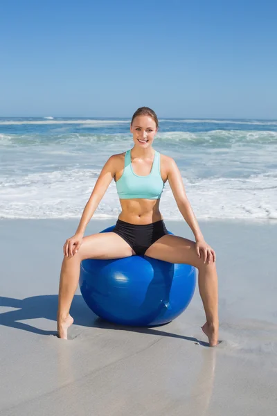 Kvinna sitter på övning boll på stranden — Stockfoto