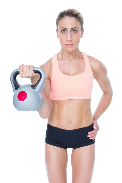 Serious female crossfitter lifting kettlebell — Stock Photo, Image