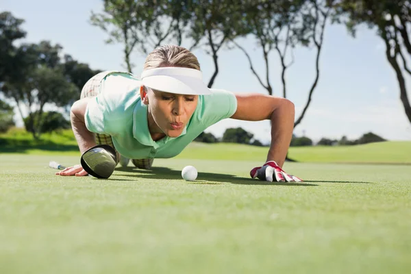 Golfer blowing her ball on putting green — Stock Photo, Image