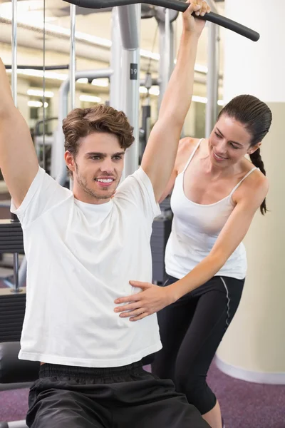 Man using weights machine with trainer — Stock Photo, Image