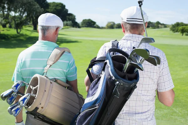 Amis golfeurs marchant tenant des sacs de golf — Photo