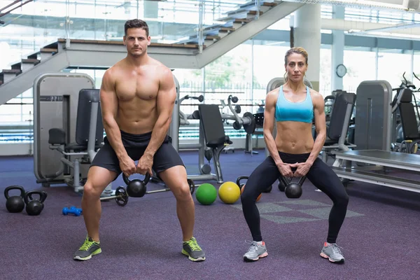 Kulturistika muži a žena, zvedání kettlebells — Stock fotografie