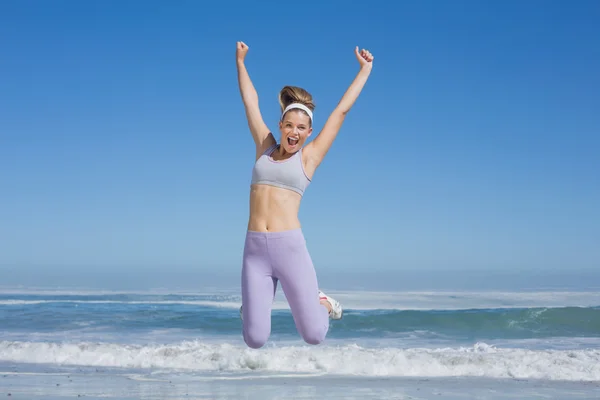Sportowy blondynka skoki na plaży — Zdjęcie stockowe