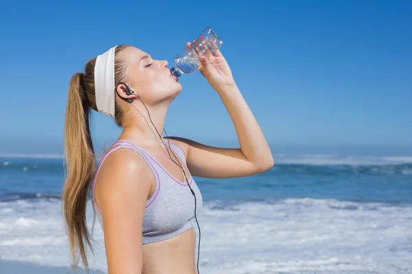 Sportig blondin på stranden och dricka vatten — Stockfoto