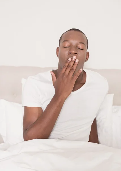 Tired man yawning in his bed — Stock Photo, Image