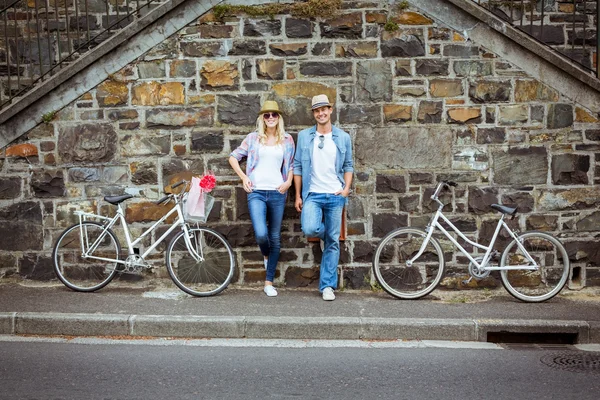 Hippes Paar steht mit Fahrrädern an Wand — Stockfoto
