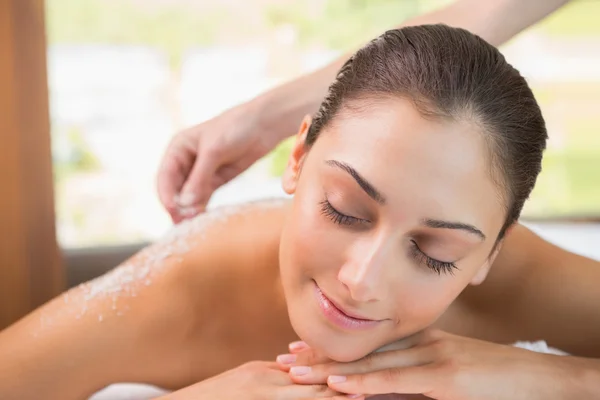 Therapist pouring salt scrub on womans back — Stock Photo, Image