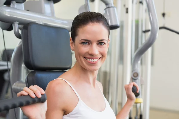 Brunette met behulp van gewichten machine voor wapens — Stockfoto