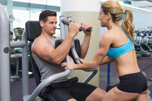 Trainer coaching bodybuilder using weight machine — Stock Photo, Image