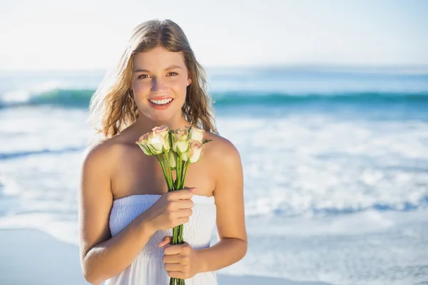 Blondynka w sukienkę trzyma róż na plaży — Zdjęcie stockowe