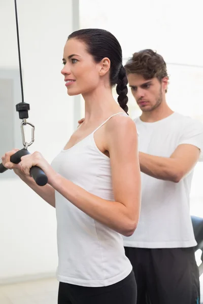 Woman using weights machine with traine — Stock Photo, Image