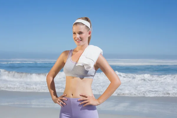 Sportig blondin stående på stranden med handduk — Stockfoto