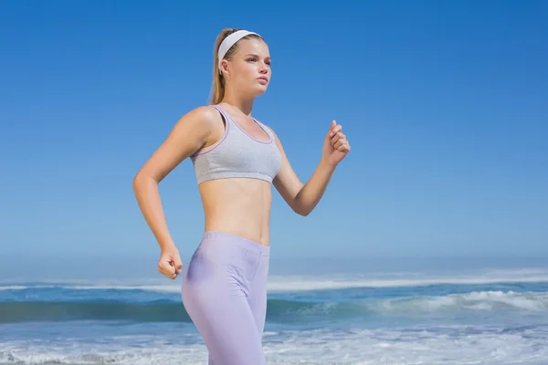 Sportowy koncentruje się blondynka jogging na plaży — Zdjęcie stockowe