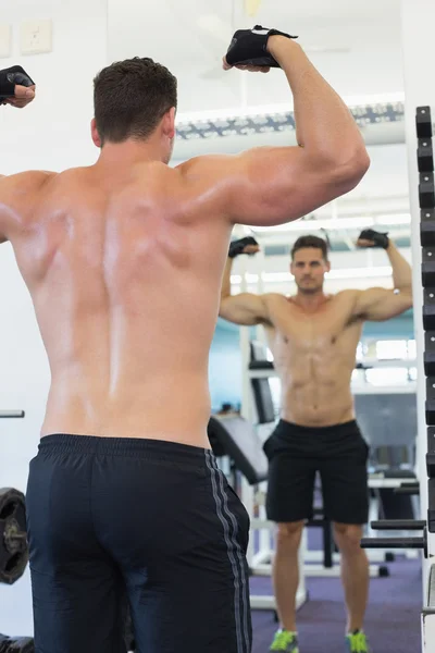 Bodybuilder flexar framför spegeln — Stockfoto