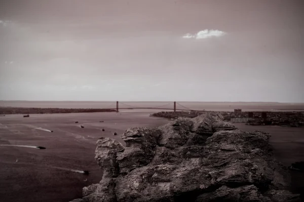 Large rock overlooking bridge over ocean — Stock Photo, Image