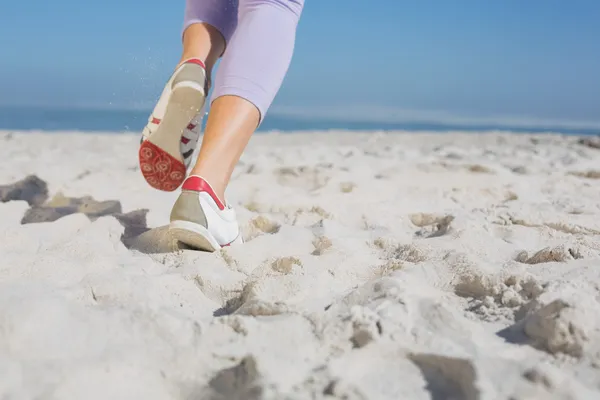 在沙滩上慢跑的运动型女人脚 — 图库照片
