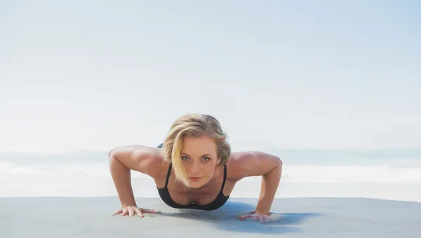 Blonde in plank positie op strand — Stockfoto