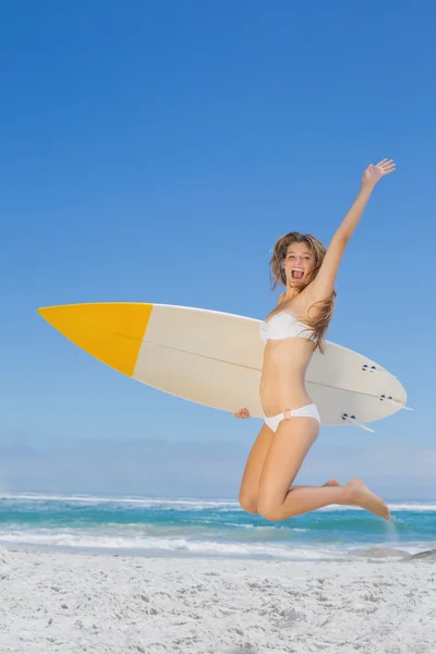 Surfista chica sosteniendo su tabla de surf y saltar — Foto de Stock