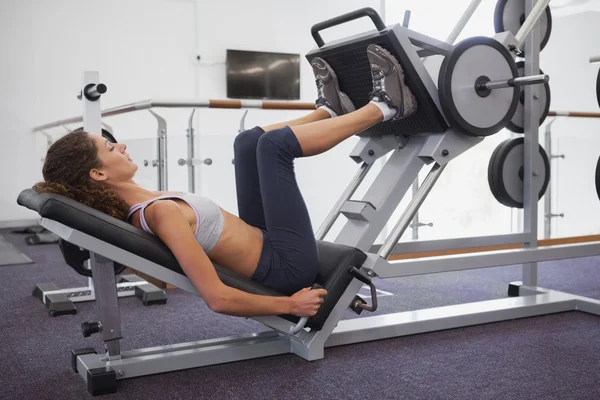 Woman using weights machine for legs — Stock Photo, Image