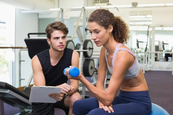 Trainer watching client lift dumbbells — Stock Photo, Image