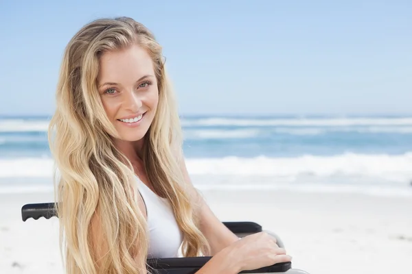 Rollstuhlgebundene Blondine lächelt am Strand — Stockfoto