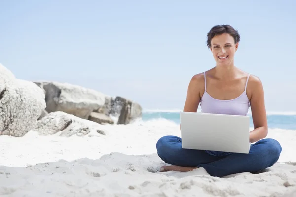 Brunette met behulp van laptop op strand — Stockfoto