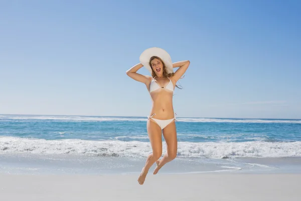 Vrouw in bikini springen op strand — Stockfoto