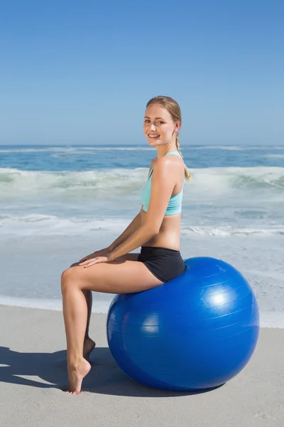 Vrouw zitten op oefening bal op strand — Stockfoto