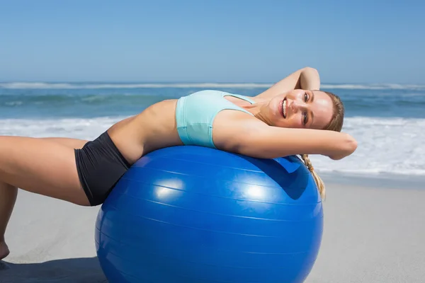 Woman lying on exercise ball at beach — Stock Photo, Image