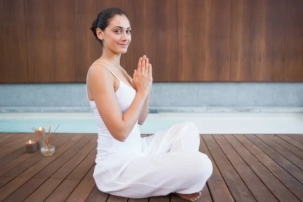 Brunette in white sitting in lotus pose — Stock Photo, Image