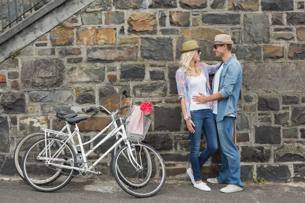 Hip couple hugging by wall with bikes — Stock Photo, Image