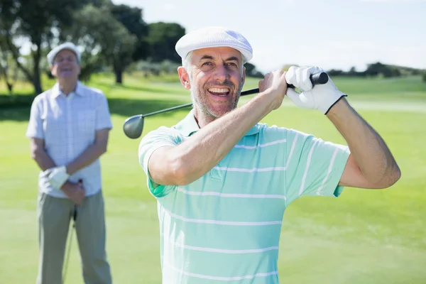 Golfista balançando seu clube com amigo — Fotografia de Stock