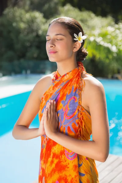 Brunette in sarong mediteren bij het zwembad — Stockfoto