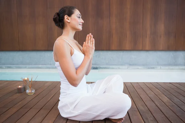 Brunette in white sitting in lotus pose — Stock Photo, Image