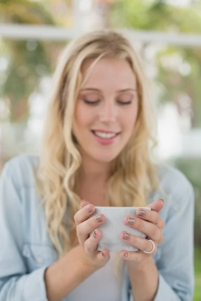 Блондинка сидит за столом и пьет кофе — стоковое фото